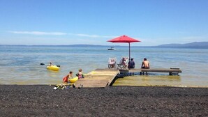 A beach with kayaks, a wooden dock, and a red umbrella. - Magma Lodge Pucon (Pucón)