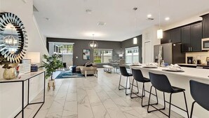 A modern kitchen with dark cabinets, a white countertop, and bar stools. - CG236OCA - Luxury 5BR-4BA Villa with Private Pool (Davenport)