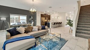A modern living room with a sofa, coffee table, and a dining area with chairs. - CG236OCA - Luxury 5BR-4BA Villa with Private Pool (Davenport)