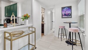 Une cuisine moderne avec des meubles blancs, un robinet doré et un petit coin bar équipé de tabourets.