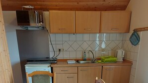 A compact kitchen with wooden cabinets, a sink, and a table set for dining. - Vacation at the Uhlenhoff Apartment Ewiges Meer (Ihlow)