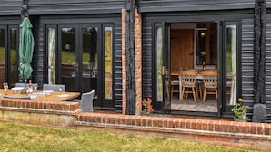 Une maison en bois noire dotée d’un coin repas et d’une terrasse.