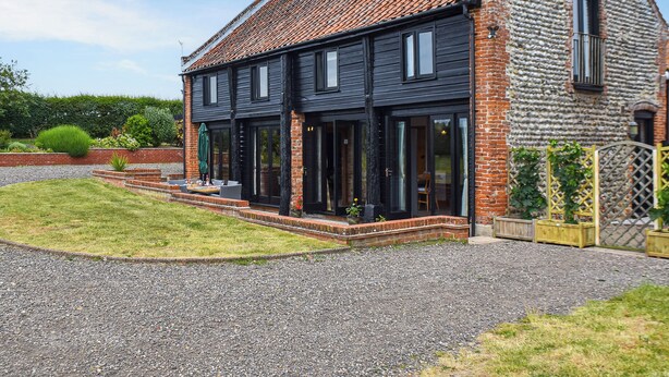 Une maison à deux étages, avec un toit en tuiles, une façade en briques et de grandes fenêtres.