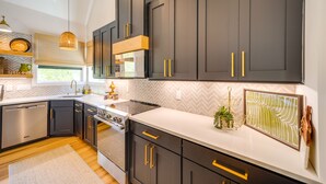 Una cocina moderna con armarios oscuros, electrodomésticos de acero inoxidable y un salpicadero con diseño tipo espiga.