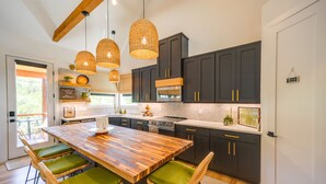 Una cocina moderna con armarios oscuros, una isla de madera y lámparas colgantes de mimbre.