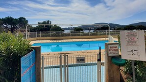 A swimming pool with a view of a lake and mountains in the background. There are signs indicating the pool is private and reserved. - Lumineux appartement avec vue sur mer (Saint-Raphaël)