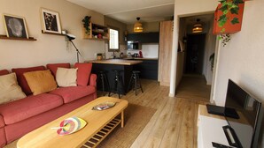 A cozy living room with a red sofa, a wooden coffee table, and a TV. - Lumineux appartement avec vue sur mer (Saint-Raphaël)