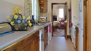 Une cuisine étroite avec des meubles de rangement en bois, un four à micro-ondes et un coin repas comprenant une table et des chaises.