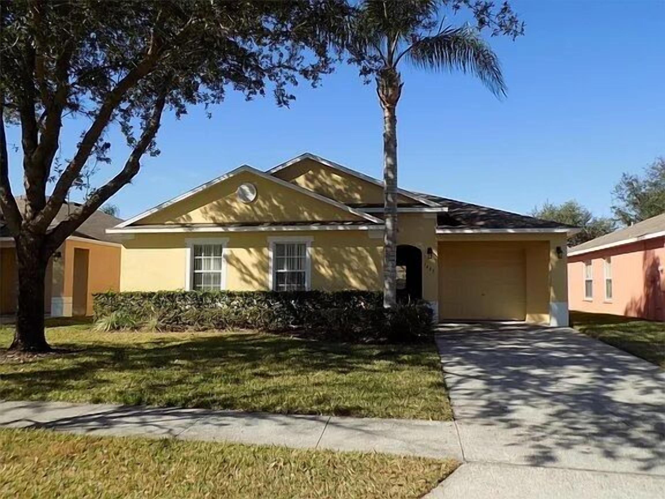 A single-story house with a yellow facade, a front porch, and a well-maintained lawn.