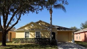 A single-story house with a yellow facade, a front porch, and a well-maintained lawn. - Lovely 3-Bedroom Pool With Spa (Clermont)