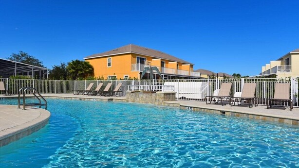 A swimming pool with lounge chairs and a building in the background.