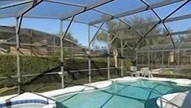 A glass-enclosed swimming pool with a hot tub, surrounded by a metal frame and glass panels. - Lovely 3-Bedroom Pool With Spa (Clermont)