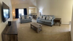 A living room with two sofas, a coffee table, and a TV on a stand. - Lovely 3-Bedroom Pool With Spa (Clermont)