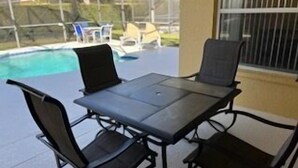 An outdoor patio with a table and chairs, a pool, and a view of the backyard. - Lovely 3-Bedroom Pool With Spa (Clermont)