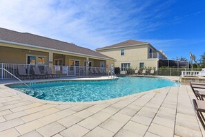 A swimming pool with lounge chairs and a building with a flat roof.