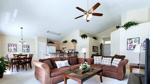 Ein Wohnzimmer mit Ecksofa, Couchtisch, Deckenventilator und Fernseher.