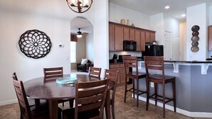 Une cuisine moderne avec des meubles en bois, un îlot central et un coin repas comprenant une table ronde et des chaises.