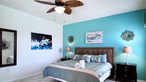 Une chambre à coucher comprenant un lit, un ventilateur de plafond, une table de chevet, une lampe et des éléments décoratifs sur les murs.