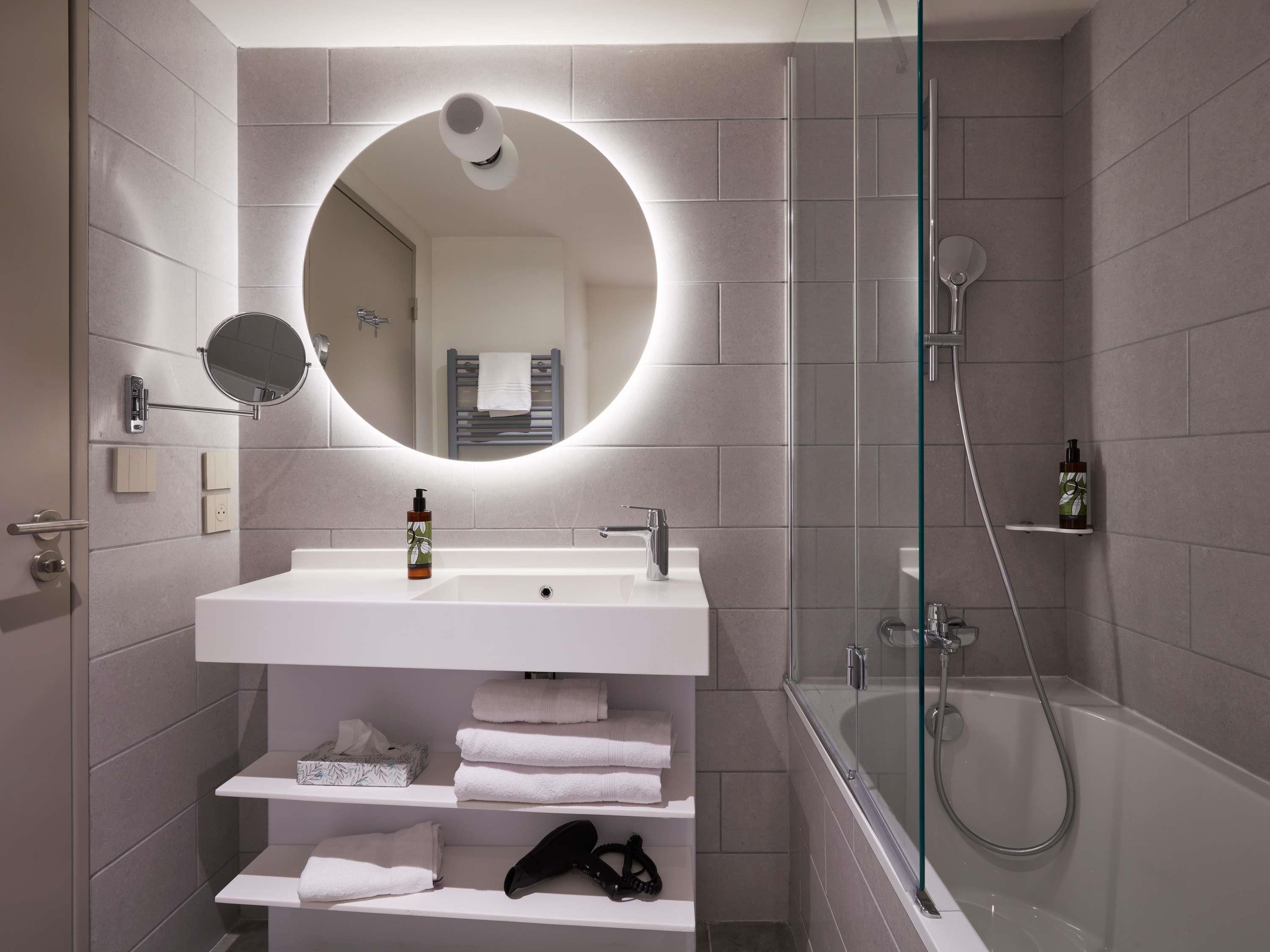 A modern bathroom with a white sink, mirror, and glass-enclosed shower.