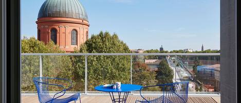 A balcony with a view of a large dome building, a table with chairs, and a railing.