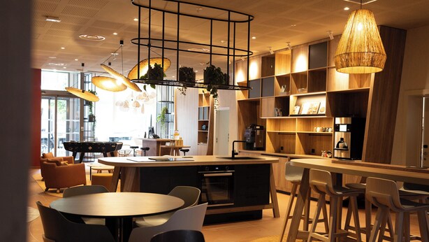 Una cocina moderna con una isla central, taburetes de bar e iluminación colgante.