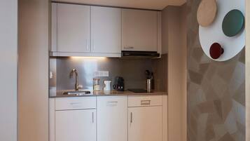 A modern kitchen with white cabinets, a stainless steel sink, and a coffee maker.