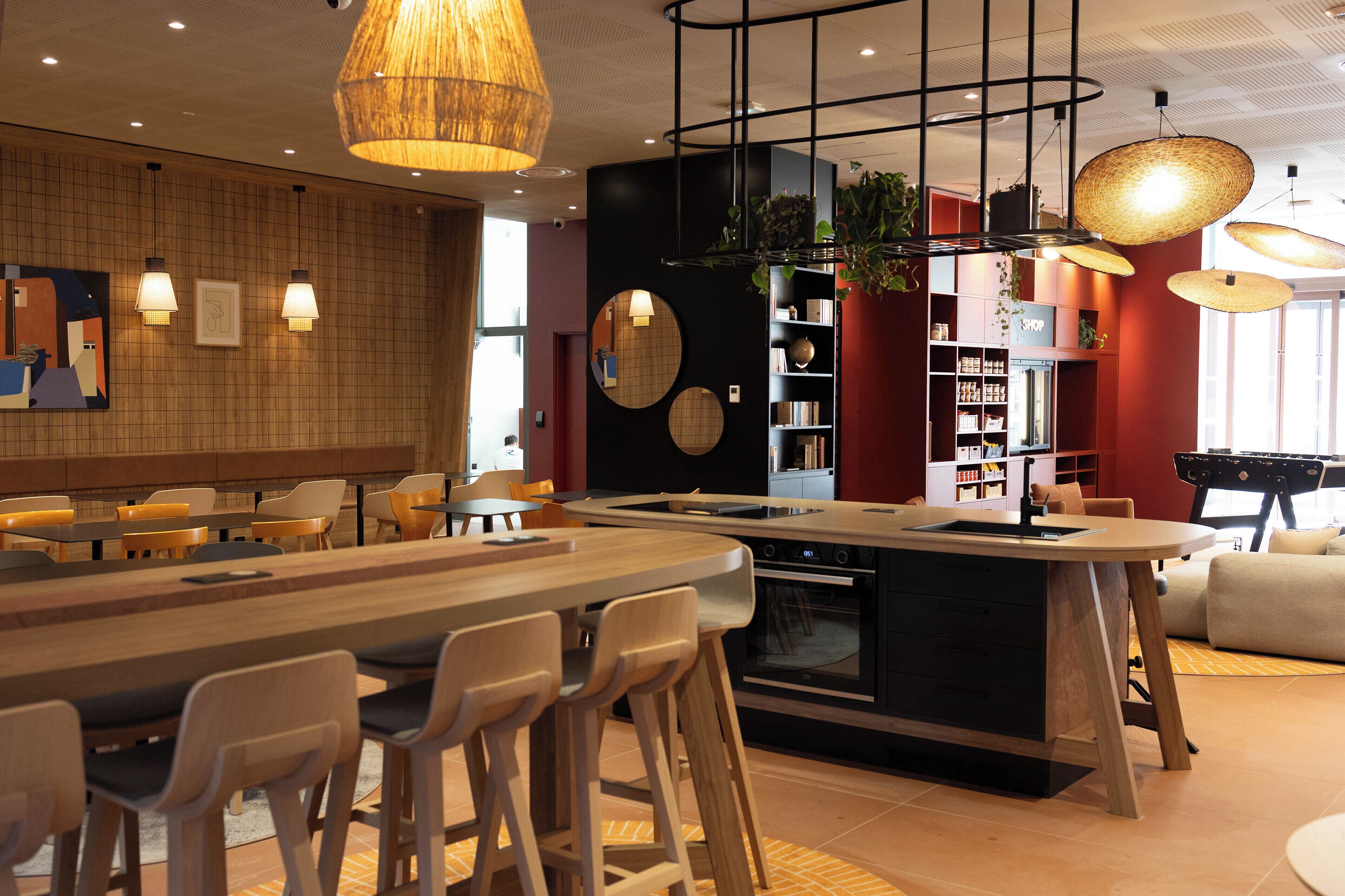 Une cuisine moderne dotée d’un îlot central, de tabourets de bar, de luminaires suspendus et d’une bibliothèque.