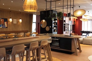 A modern kitchen with a central island, bar stools, pendant lighting, and a bookshelf. - Aparthotel Adagio Toulouse Centre La Grave (Toulouse)