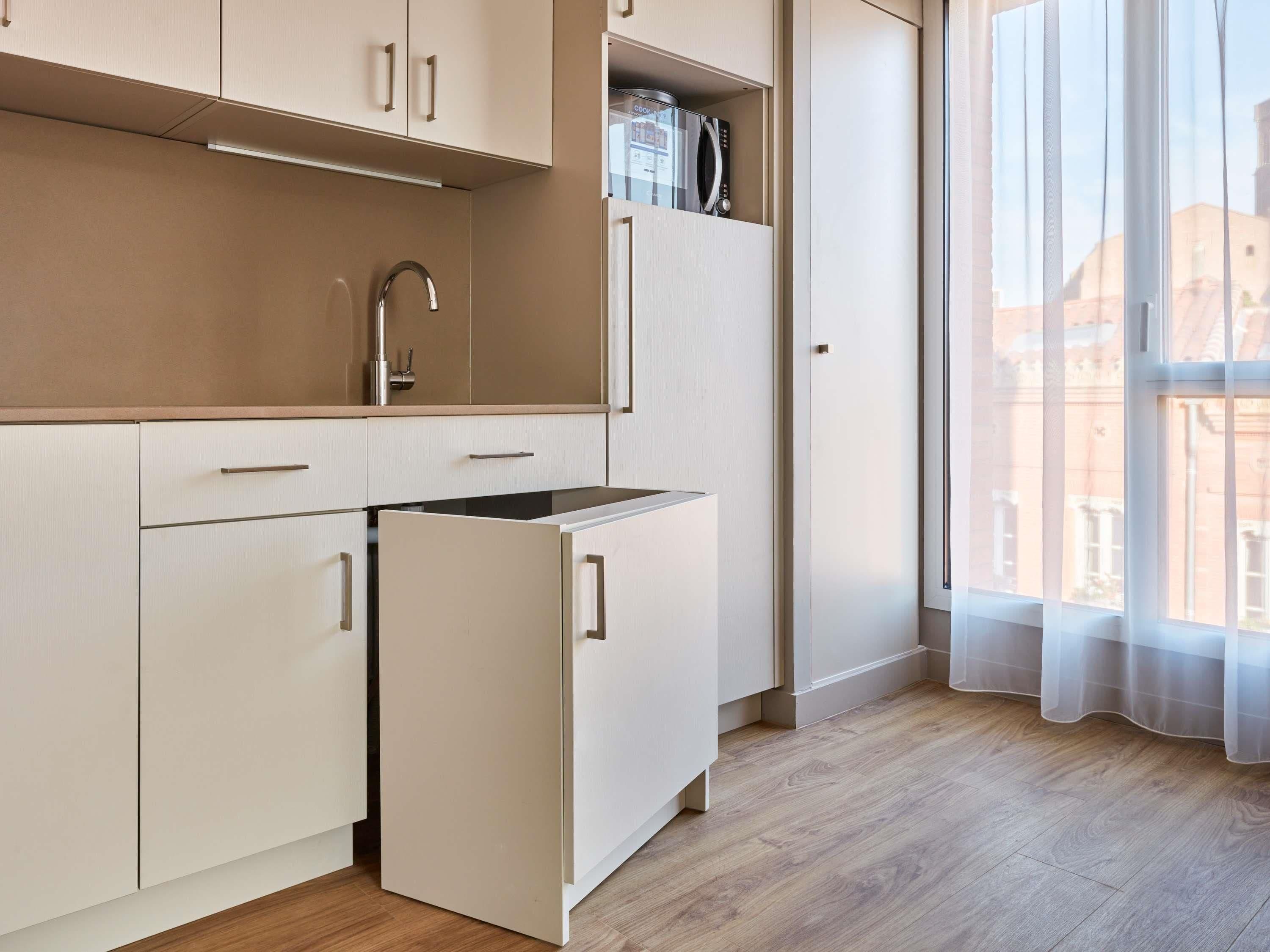 A compact kitchen with a built-in microwave, a sink, and a refrigerator.