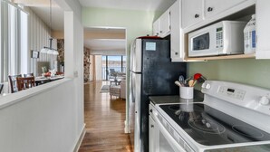 A modern kitchen with white cabinets, a black refrigerator, a microwave, and a stove.