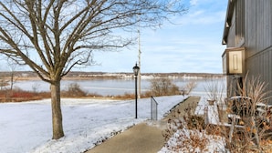 A snow-covered pathway leading to a building with a view of a lake and distant hills.