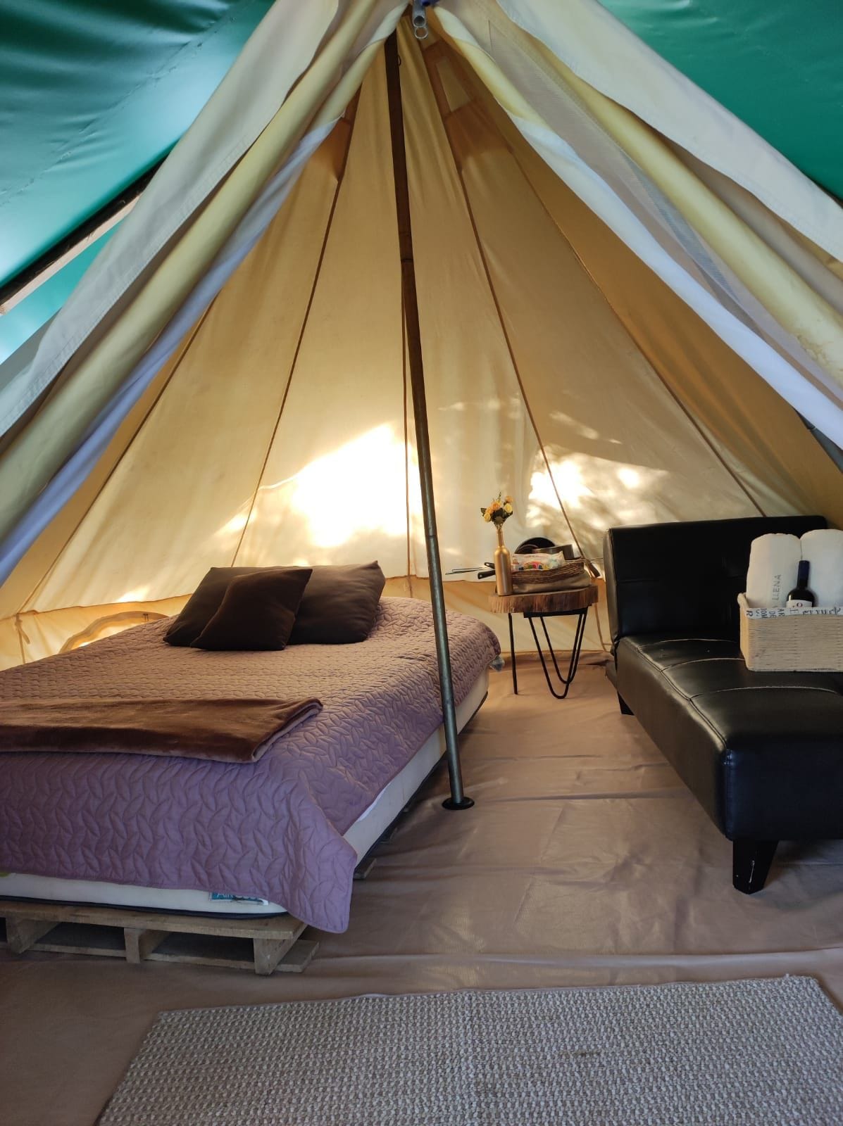 A tent with a bed, a small table, and a black chair.
