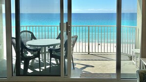 Un balcón con mesa y sillas, con vista a una playa y una vista despejada del océano.