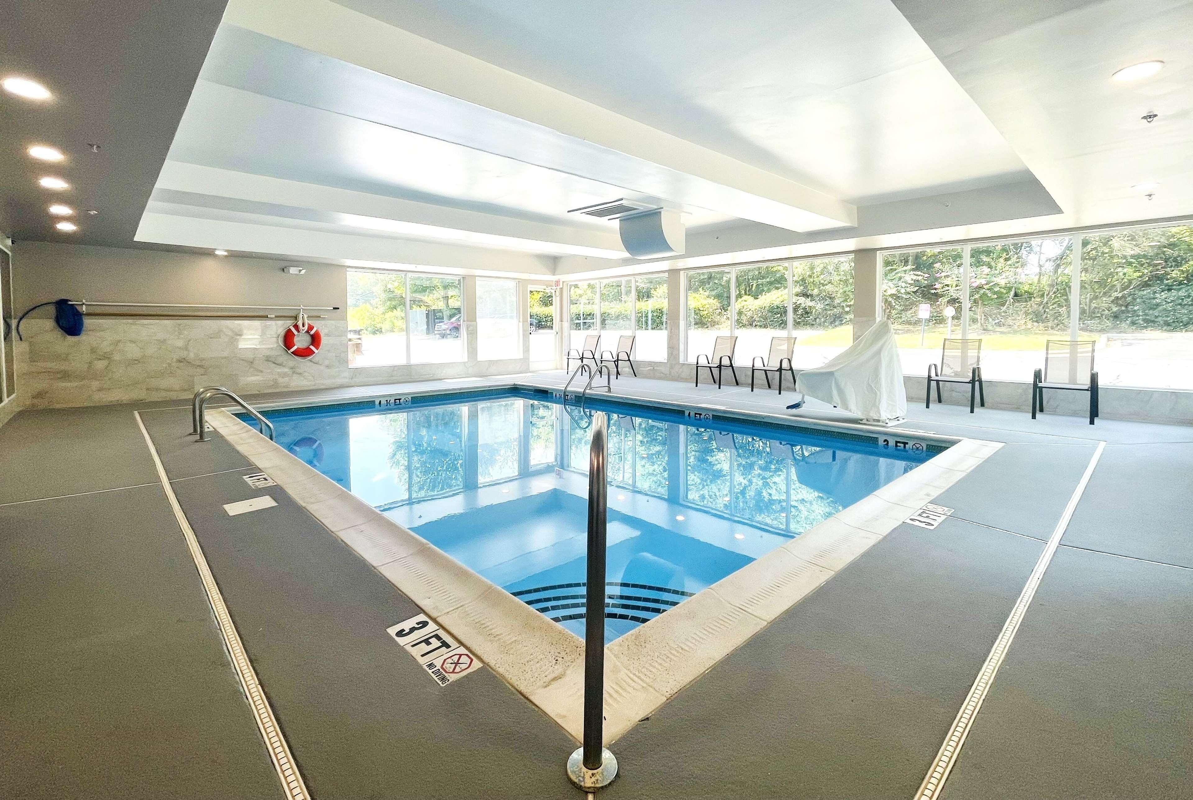 Une piscine intérieure à l’eau claire, équipée d’une bouée de sauvetage et d’un panneau indiquant une profondeur minimale de 90 cm (3 pieds) pour éviter de plonger.