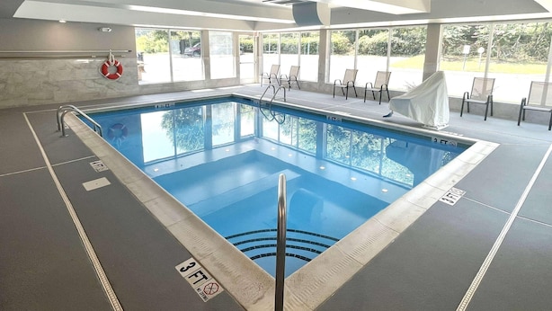 Una piscina interior con agua cristalina, un flotador salvavidas y sillas de descanso.