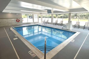 An indoor swimming pool with clear water, a lifebuoy, and lounge chairs. - Wingate By Wyndham Matthews Nc (Matthews)
