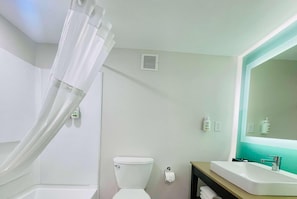 Un baño con inodoro, lavamanos, espejo y cortina de ducha.