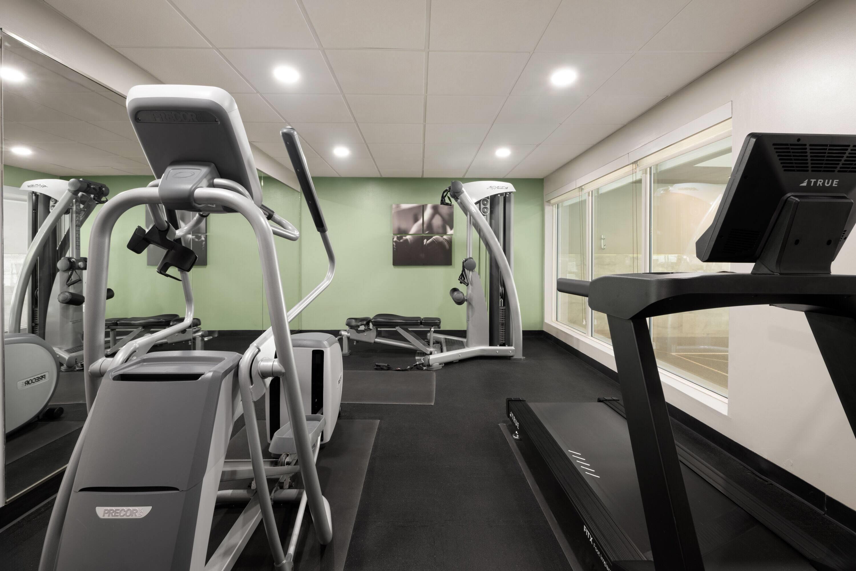 A gym with treadmills, elliptical machines, and weight equipment.
