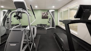 Un gimnasio con cintas de correr, elípticas y equipo de pesas.