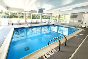 Una piscina interior con agua cristalina, un letrero de advertencia de salvavidas y una marca de profundidad de 1 metro 43.