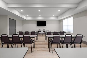 Un salón de conferencias con mesas, sillas, un televisor de pantalla plana y un ventanal grande.
