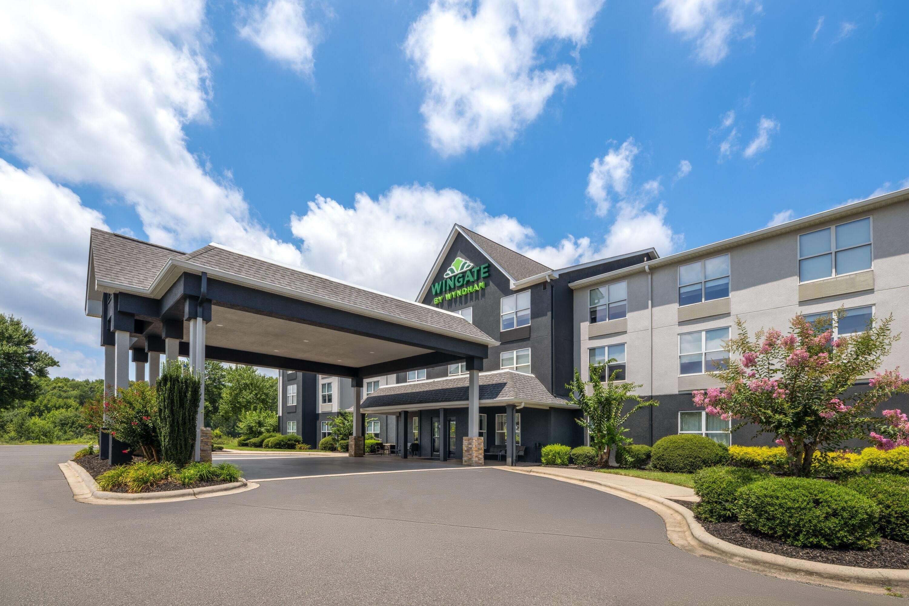 A hotel with a covered entrance, a sign reading 'Wingate by Wyndham,' and a parking lot.