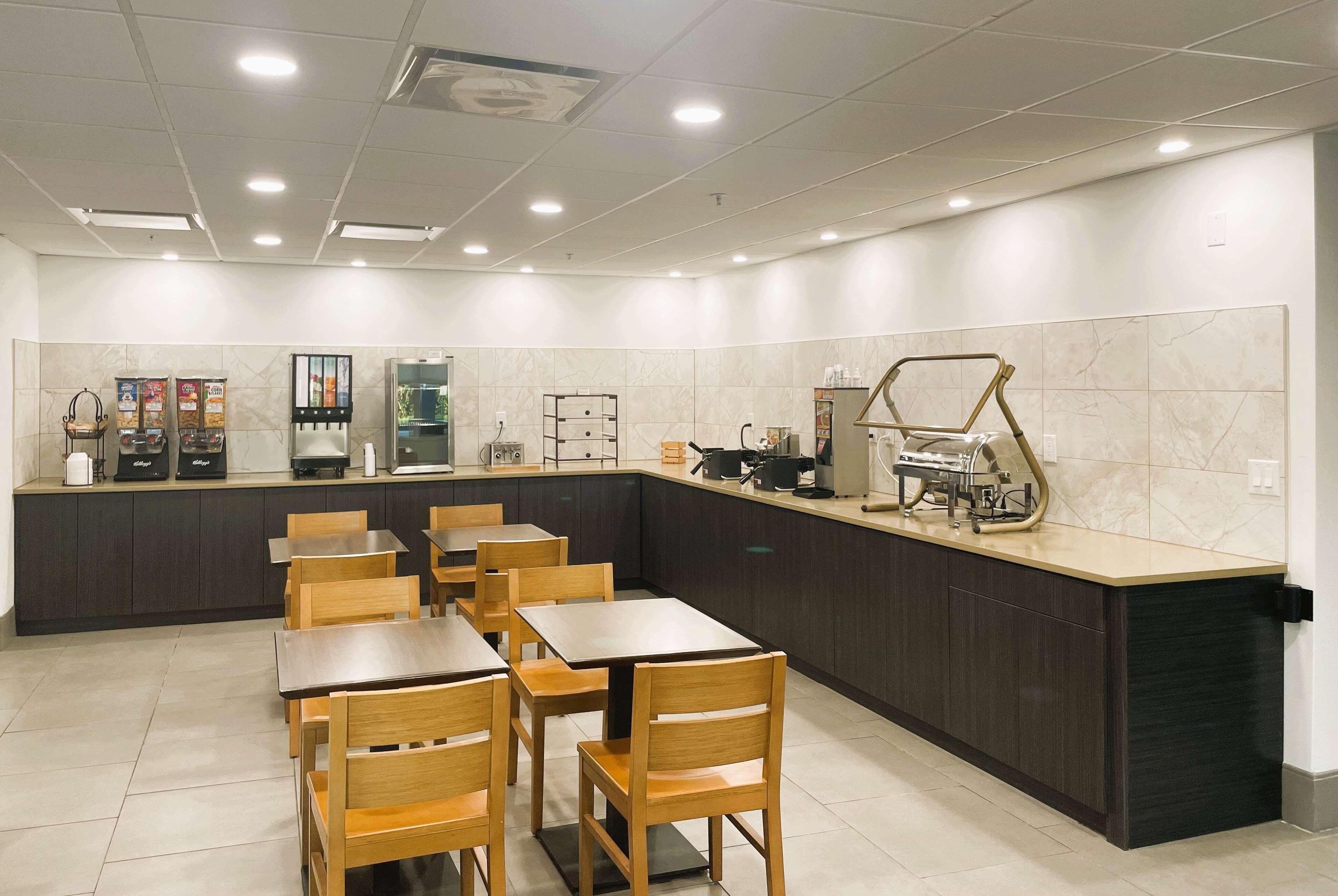 A modern restaurant with a counter, seating, and kitchen area.