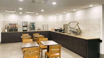 A modern restaurant with a counter, seating, and kitchen area.