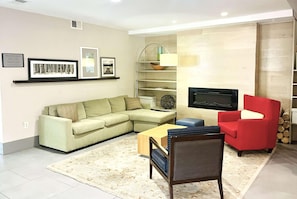A living room with a sectional sofa, a red armchair, a coffee table, a TV, and a bookshelf. - Wingate By Wyndham Matthews Nc (Matthews)