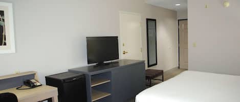 Una habitación de hotel con cama, escritorio con computadora, televisión y un pequeño espacio para sentarse.
