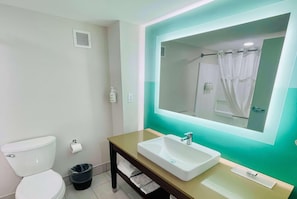 Une salle de bain Ă©quipĂ©e de toilettes, dâun lavabo, dâun miroir et dâune poubelle.