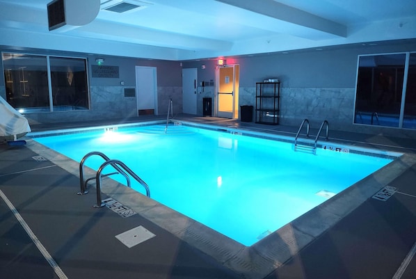An indoor swimming pool with clear water, a lifeguard warning sign, and a visible exit door. - Wingate By Wyndham Matthews Nc (Matthews)