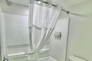 Ein Badezimmer mit Duschvorhang, Toilette und einer Handseifen-Spenderwandhalterung.