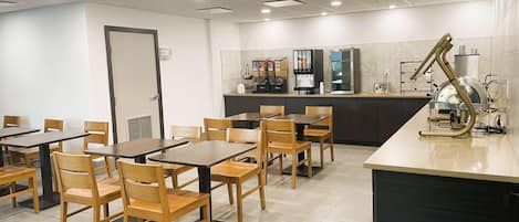 Un espace repas avec des tables et des chaises, un comptoir de cuisine avec des appareils électroménagers et une porte.